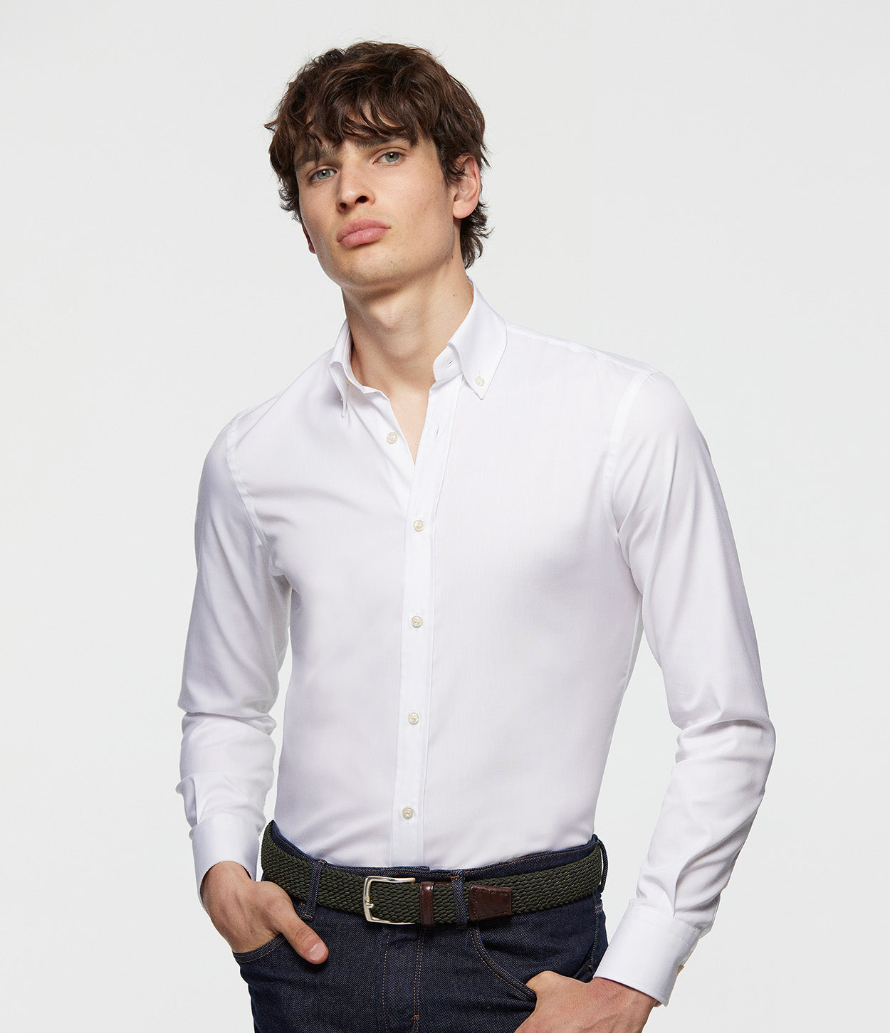 fotografía modelo de pie con las manos en el bolsillo y camisa blanca